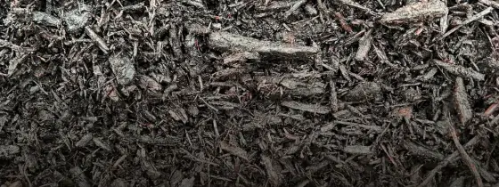 Close-up texture of black dyed shredded hardwood mulch with a few reddish undertones