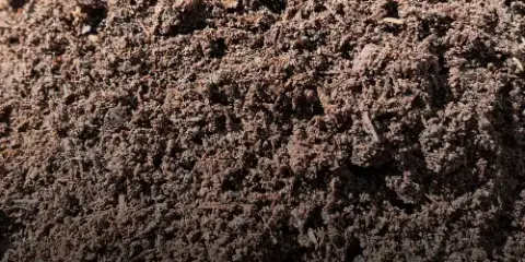 Close-up texture of dark brown fine screened compost with tiny wood fibers