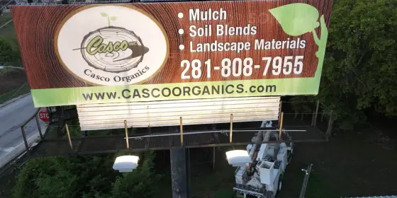 Aerial of the Casco Organics billboard in front of the freeway overpass, with the logo, the 281-808-7955 phone number and cascoorganics.com