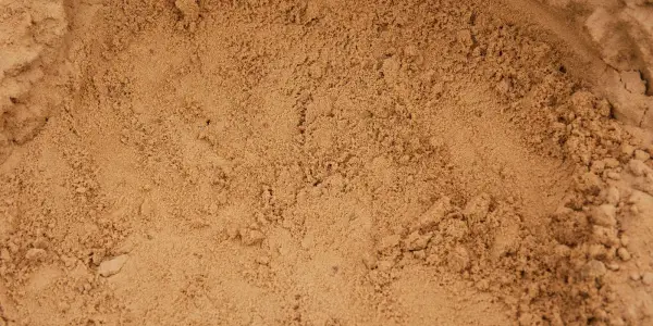 Close-up of loose tan sand with a smooth scooped hollow in the middle