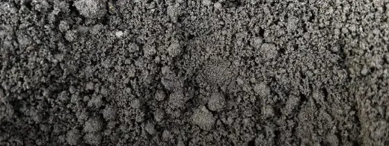 Close-up texture of dark grey crumbly screened sandy loam topsoil